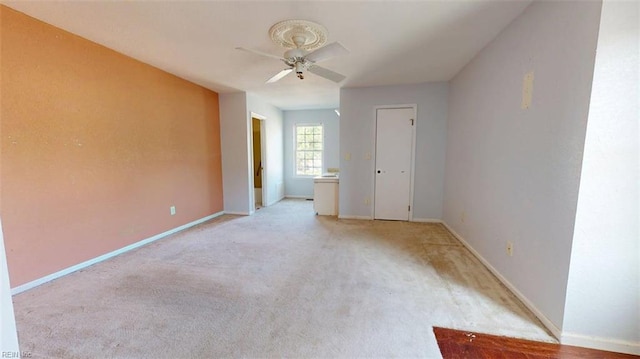 unfurnished room with a ceiling fan, baseboards, and light colored carpet
