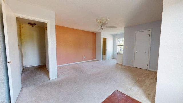 unfurnished room featuring ceiling fan, light colored carpet, and baseboards