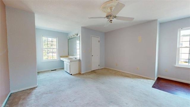 unfurnished bedroom with light carpet, baseboards, a ceiling fan, and a sink