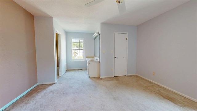 spare room featuring light carpet, baseboards, and a ceiling fan