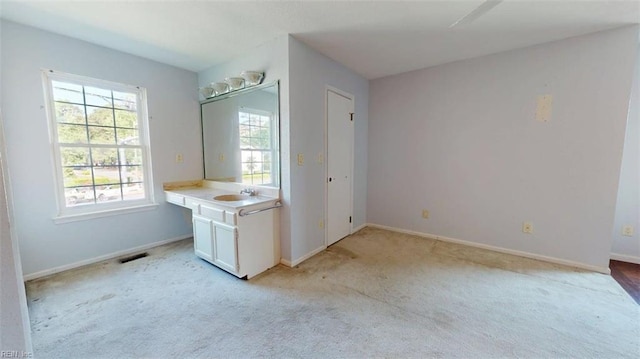 unfurnished bedroom with light carpet, baseboards, and a sink