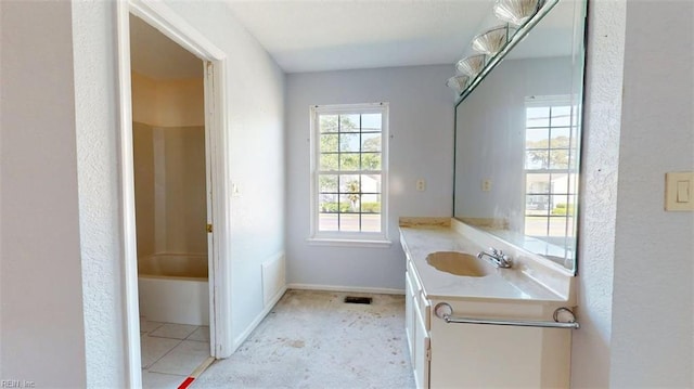 full bath with vanity, a textured wall, and baseboards