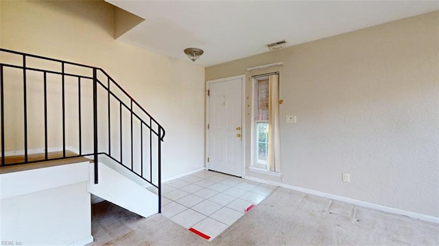 carpeted foyer featuring stairs, baseboards, and tile patterned floors