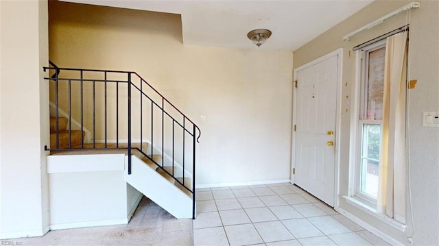 tiled entryway with stairs and baseboards