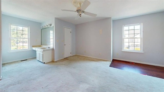 unfurnished bedroom with light colored carpet, baseboards, a ceiling fan, and a sink