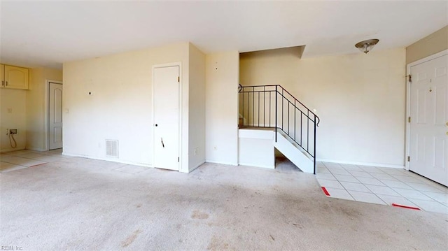 foyer featuring light carpet, stairs, and baseboards