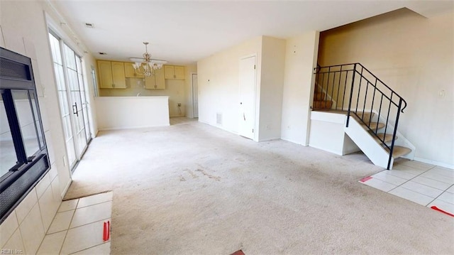 unfurnished living room with stairs, a chandelier, light colored carpet, and baseboards