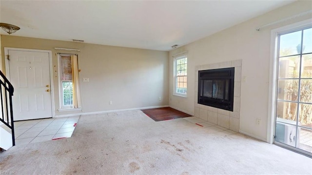 unfurnished living room with carpet flooring, a tile fireplace, and baseboards