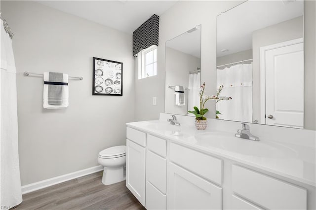full bath featuring a sink, double vanity, toilet, and wood finished floors