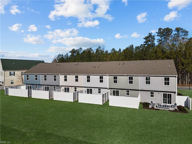 rear view of property with a lawn and fence