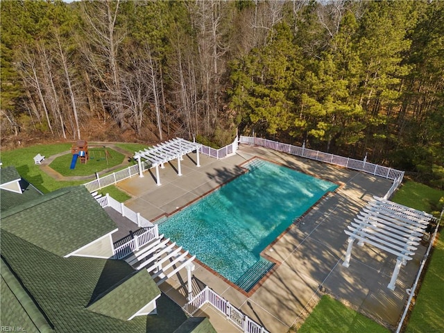 pool with fence, a pergola, a patio area, a lawn, and a view of trees