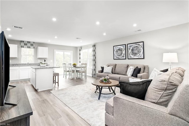 living area featuring visible vents, recessed lighting, light wood finished floors, and a healthy amount of sunlight