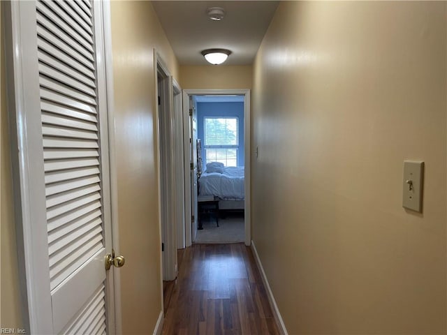 corridor featuring baseboards and dark wood-style floors