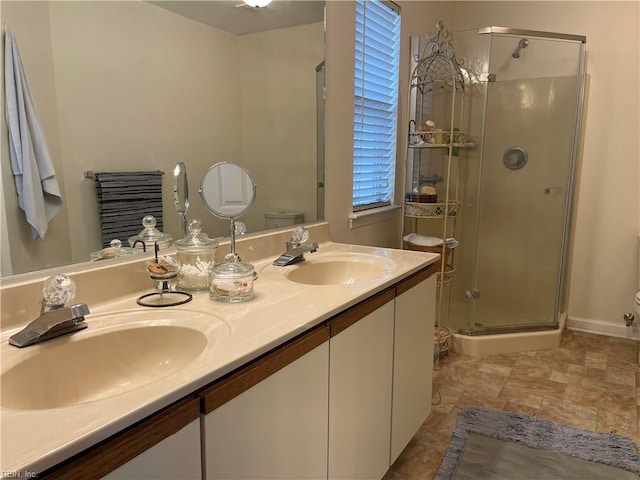full bath featuring double vanity, a sink, toilet, and a shower stall