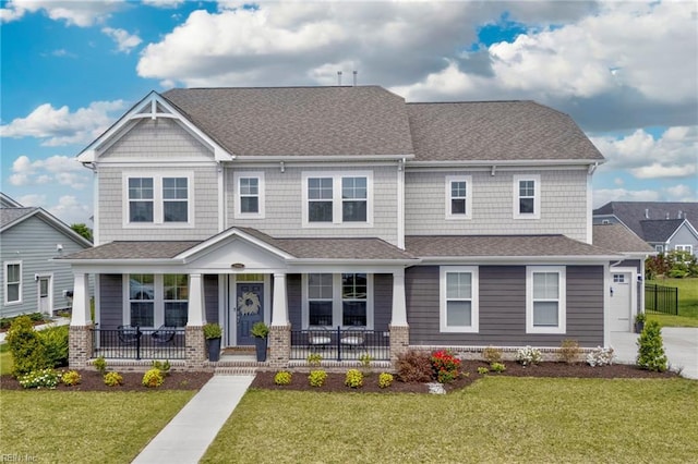 craftsman-style home featuring covered porch, a shingled roof, and a front yard