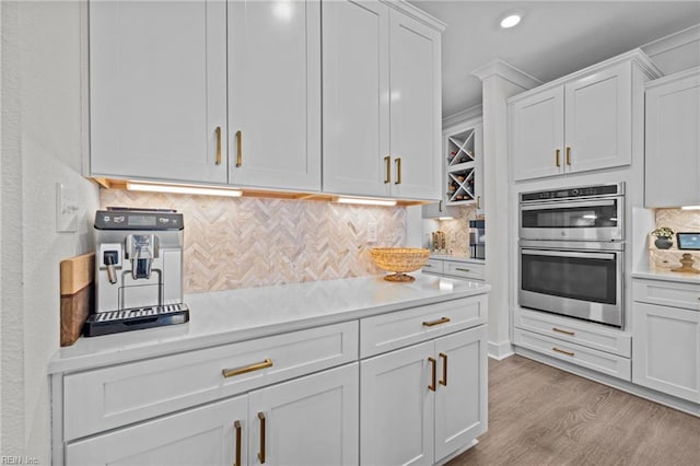 kitchen with light countertops, tasteful backsplash, double oven, and white cabinetry