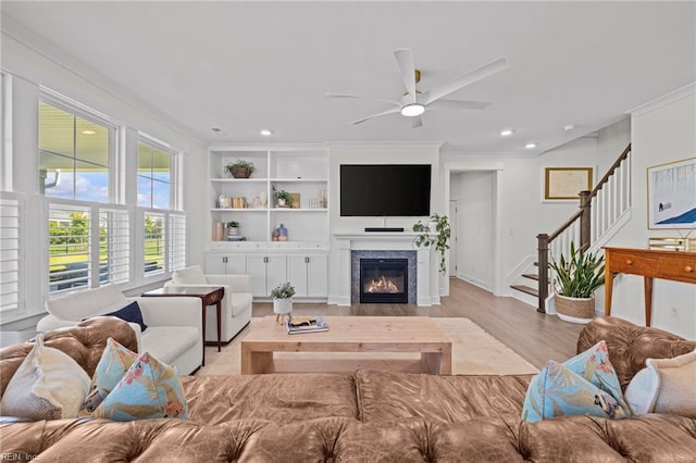 living room featuring stairs, ceiling fan, ornamental molding, and light wood-style floors