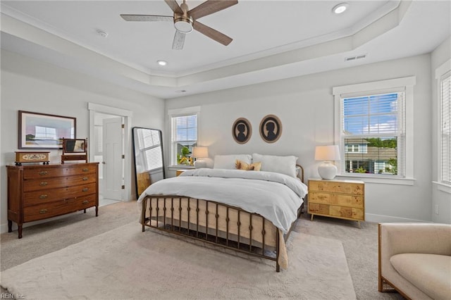 carpeted bedroom with crown molding, a tray ceiling, visible vents, and ceiling fan