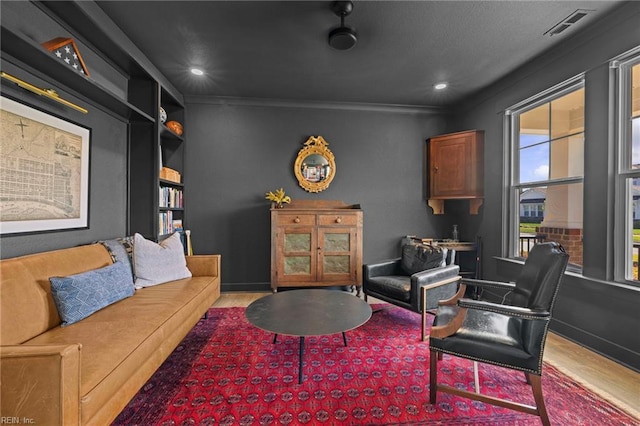 living area featuring visible vents, wood finished floors, baseboards, ornamental molding, and recessed lighting