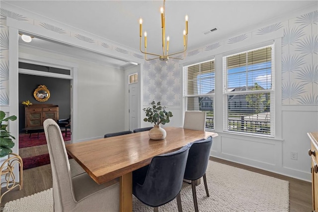 dining space with visible vents, wainscoting, wood finished floors, wallpapered walls, and a chandelier