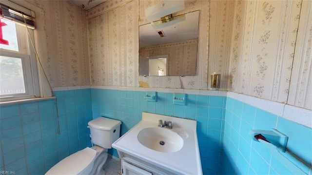 3702 Nansemond Pkwy, Suffolk, VA 23435 - half bathroom featuring wallpapered walls, toilet, a wainscoted wall, vanity, and tile walls