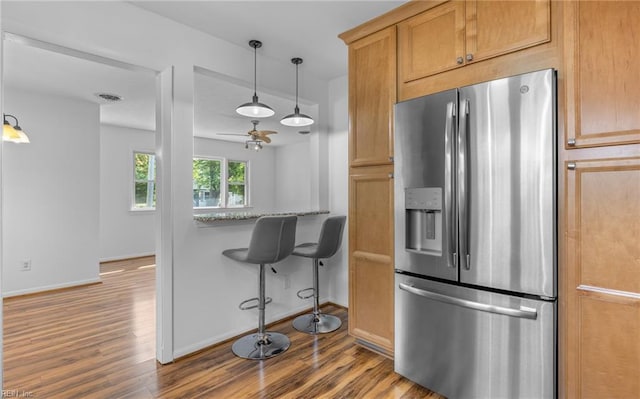 kitchen featuring visible vents, baseboards, dark wood-style floors, stainless steel fridge, and hanging light fixtures