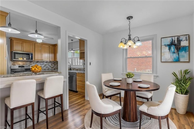 dining area with light wood-style flooring and ceiling fan with notable chandelier