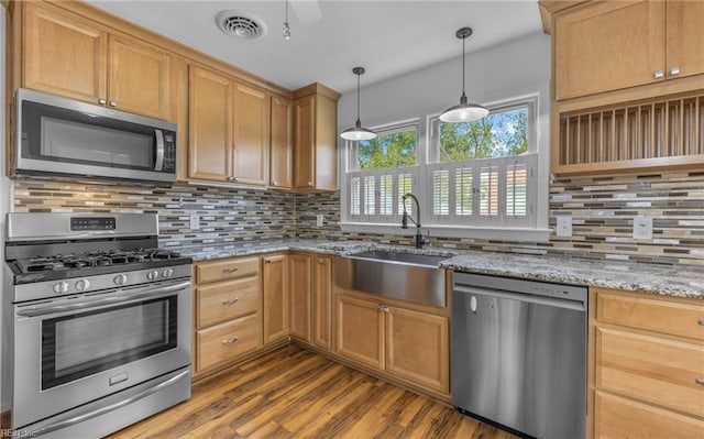 kitchen with a sink, dark wood finished floors, stainless steel appliances, tasteful backsplash, and visible vents