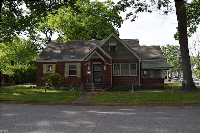view of front facade featuring brick siding, a front lawn, and a fenced front yard