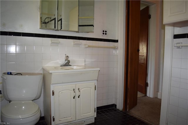 half bath with vanity, tile patterned floors, toilet, and tile walls