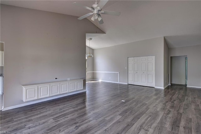 unfurnished living room with dark wood-style flooring, baseboards, ceiling fan with notable chandelier, and high vaulted ceiling