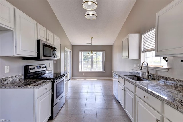 kitchen with white cabinets, appliances with stainless steel finishes, a sink, and vaulted ceiling