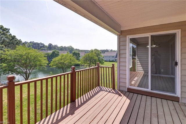 wooden terrace with a water view and a yard