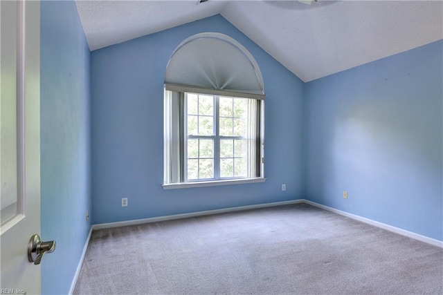 carpeted spare room with baseboards, a textured ceiling, and lofted ceiling