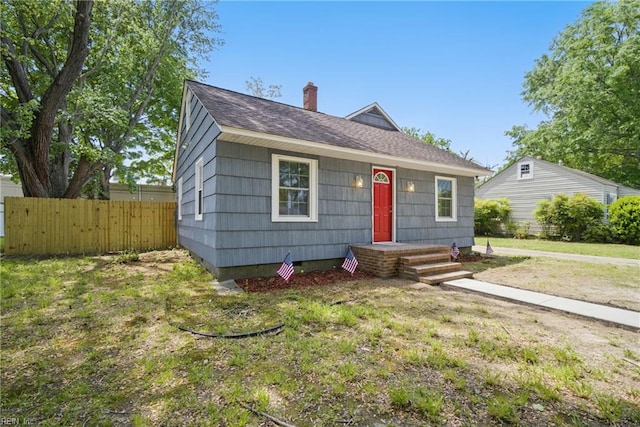 view of front of home with fence, a chimney, a shingled roof, and a front yard