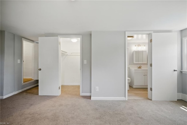 unfurnished bedroom with a closet, a sink, carpet, and a spacious closet