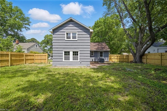 rear view of house with a lawn, central AC, and a fenced backyard