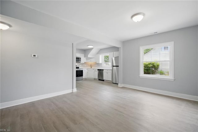 unfurnished living room featuring light wood-style floors and baseboards