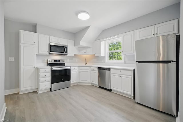 kitchen with light wood-type flooring, light countertops, white cabinetry, a sink, and appliances with stainless steel finishes
