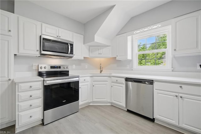 kitchen featuring a sink, appliances with stainless steel finishes, light wood finished floors, and light countertops
