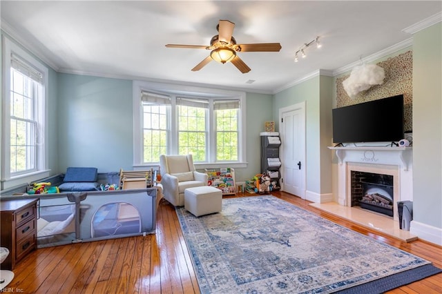 living area featuring crown molding, ceiling fan, a healthy amount of sunlight, and hardwood / wood-style floors