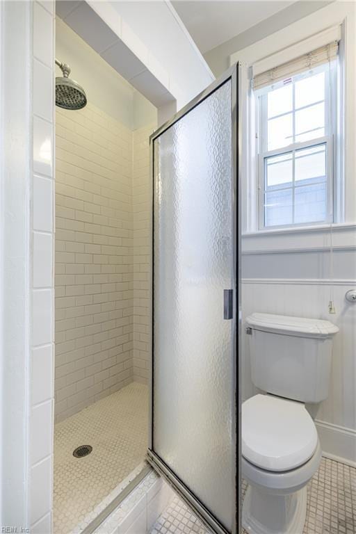 bathroom with tile patterned floors, toilet, and a shower stall