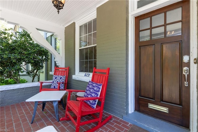 property entrance with a porch and brick siding
