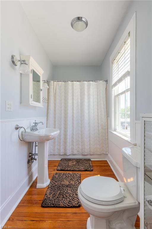 bathroom featuring a wainscoted wall, toilet, and wood finished floors