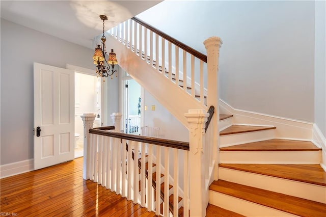stairs with an inviting chandelier and hardwood / wood-style flooring