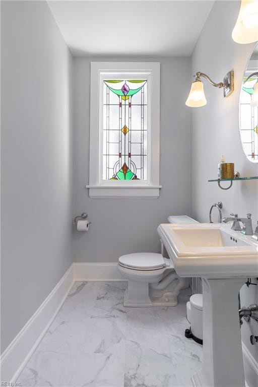half bathroom with toilet, baseboards, and marble finish floor