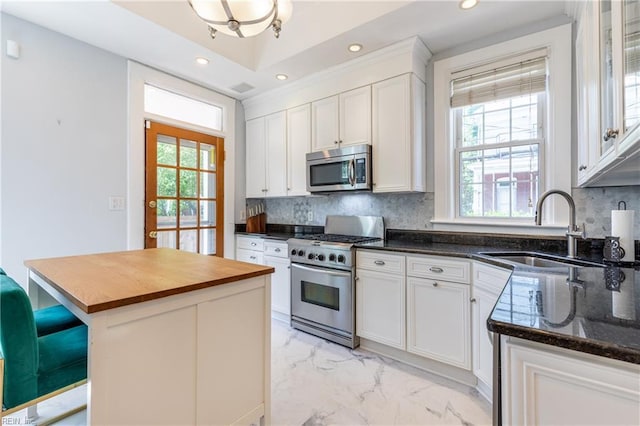 kitchen with a center island, a sink, marble finish floor, wood counters, and stainless steel appliances