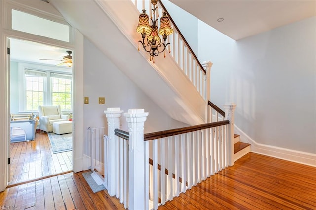 staircase featuring wood-type flooring, baseboards, and a notable chandelier