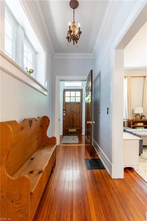 foyer with an inviting chandelier, ornamental molding, and hardwood / wood-style flooring