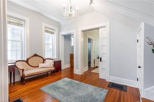 sitting room featuring crown molding, a chandelier, hardwood / wood-style floors, baseboards, and visible vents